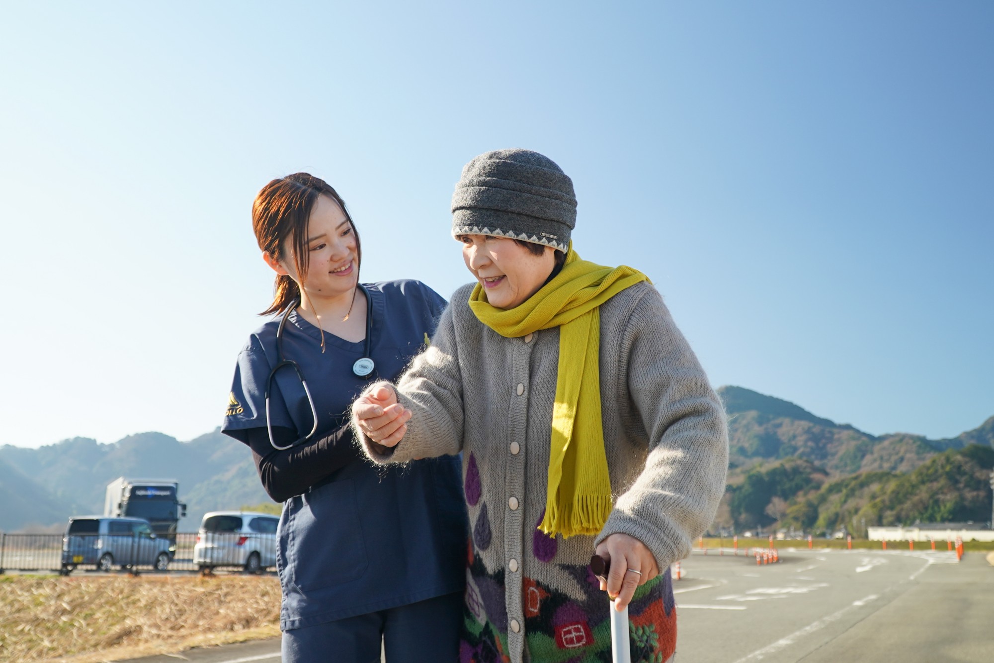 訪問看護師が利用者の手を取り、笑顔で寄り添う様子
